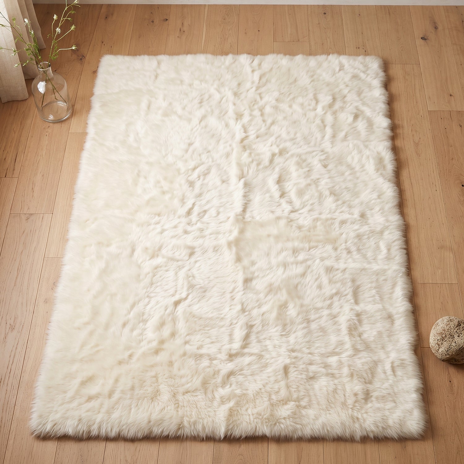 Fluffy faux fur mat laid beside a bed