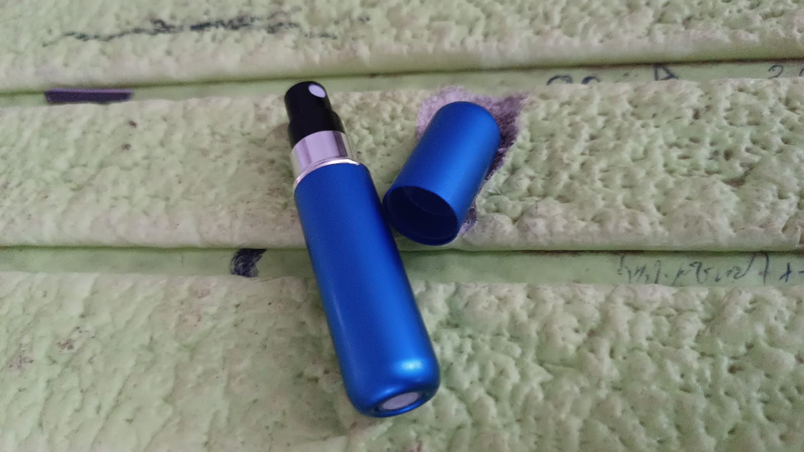 Mini perfume spray bottle next to perfume container