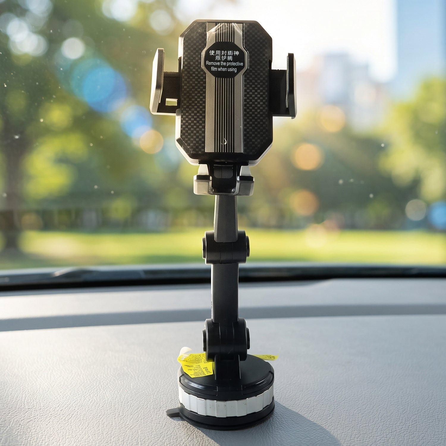 A black car mount phone holder with a textured grip and silver-ringed base is positioned on a car dashboard, with a blurred