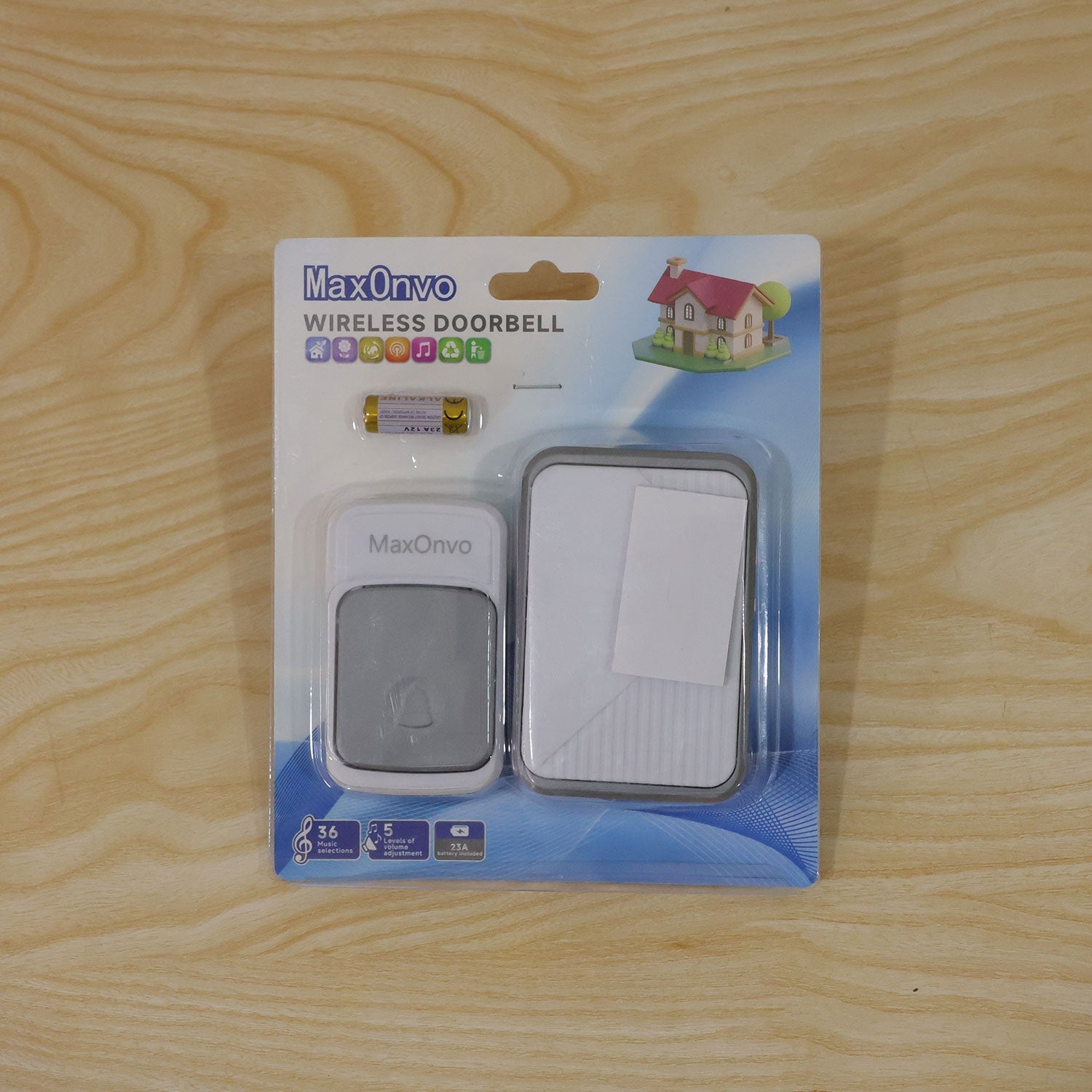 A wireless doorbell set, including the chime, button, and batteries, sealed in clear plastic packaging on a light wooden