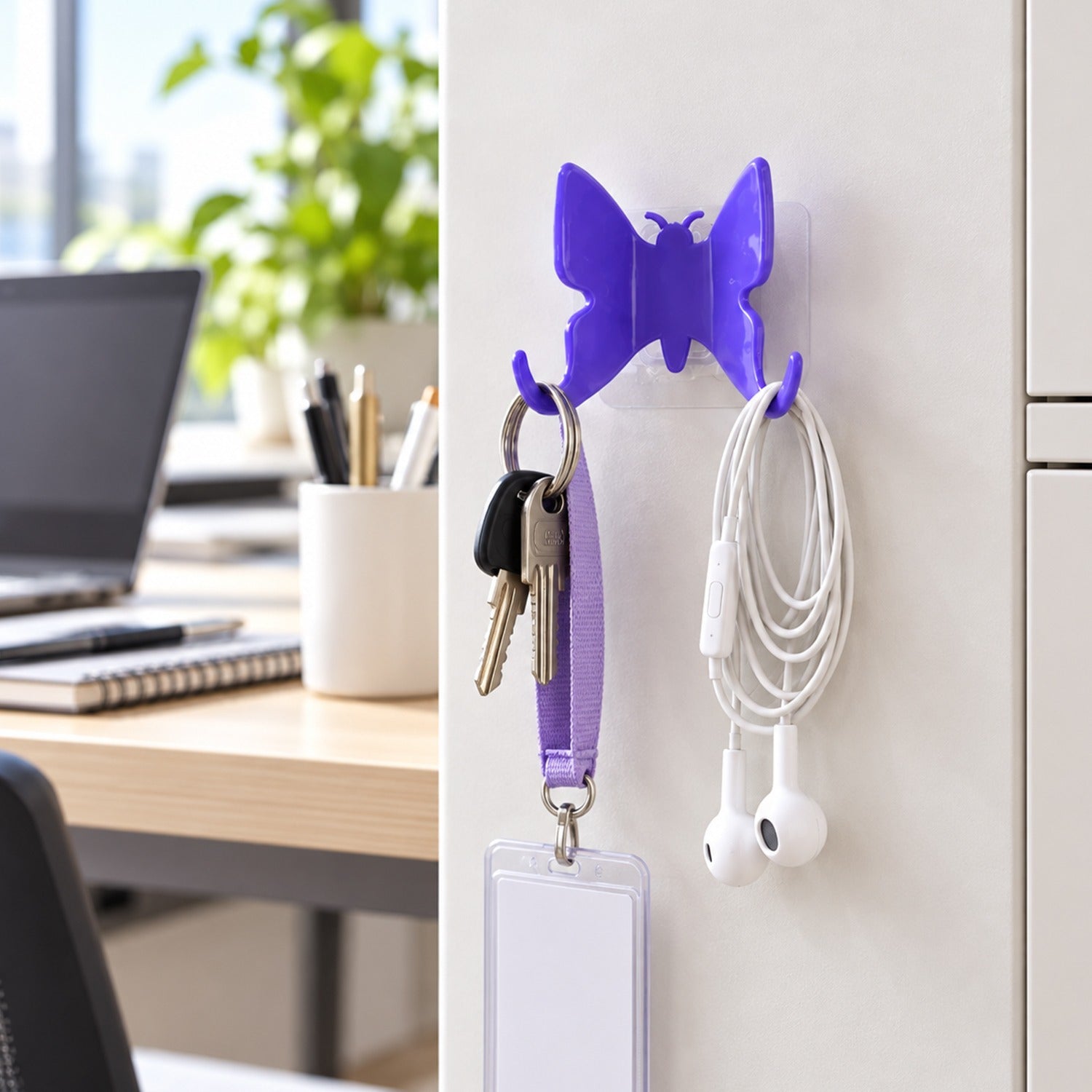 A vibrant purple butterfly-shaped hook holds keys and white earphones on a light office wall.