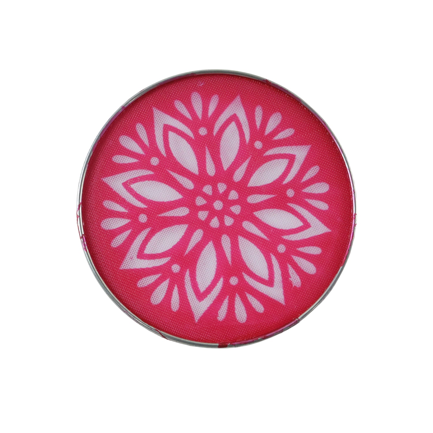 A close-up top view of a circular rangoli stencil with an intricate white floral pattern on a bright pink background.