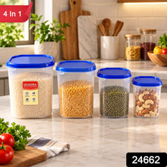 Four clear plastic containers with blue lids, filled with various dry goods, on a kitchen counter with a window behind.