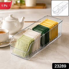 Clear plastic tea bag organizer with green, white, and yellow tea bags, shown on a kitchen counter with a teapot and cup.