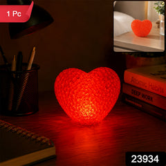 A red heart-shaped LED night lamp glows on a dark desk, with a small inset showing it on a light nightstand.