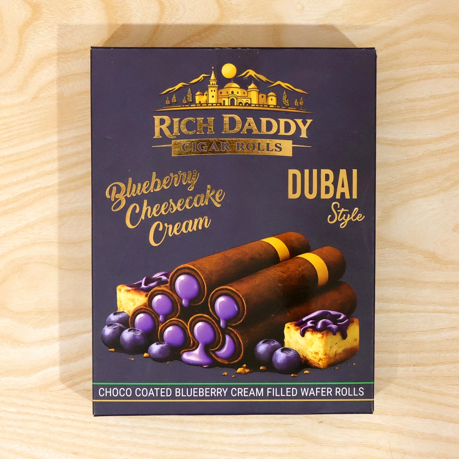 A Rich Daddy Cigar Rolls box, blueberry cheesecake cream flavor, rests on a light wooden surface.